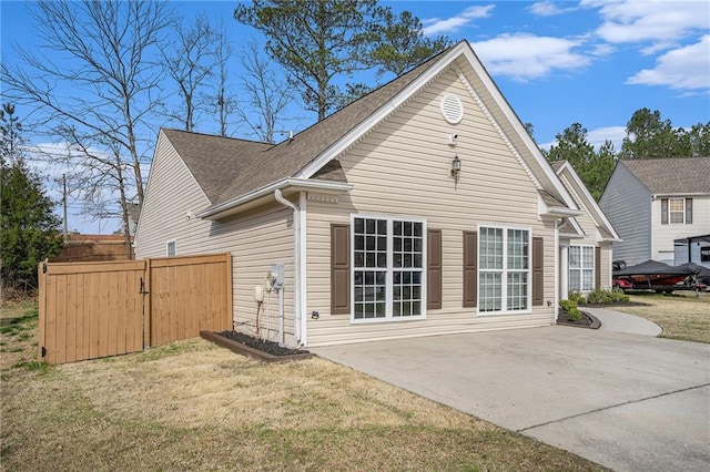 exterior space featuring a lawn, roof with shingles, a patio, and fence