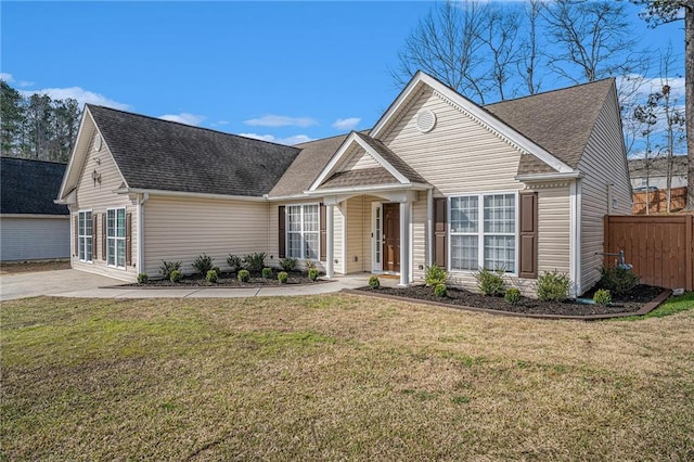 view of front of home featuring roof with shingles, a front yard, and fence