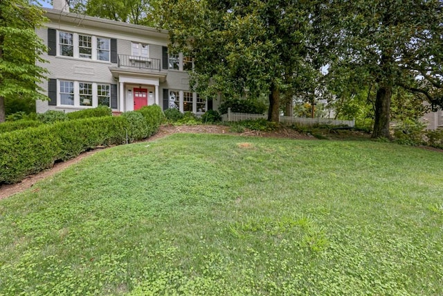 view of front of home with a balcony and a front yard