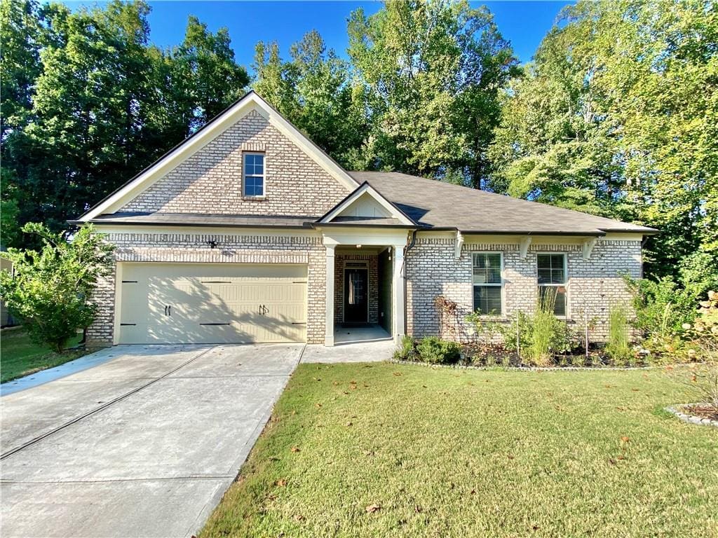 view of front of house featuring an attached garage, a front lawn, concrete driveway, and brick siding