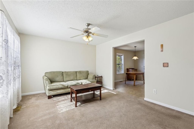 living room featuring a textured ceiling, ceiling fan, and light carpet