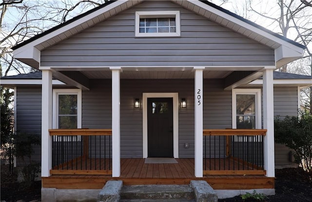 bungalow-style house featuring a porch and roof with shingles