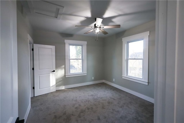 spare room featuring ceiling fan, dark carpet, a wealth of natural light, and baseboards