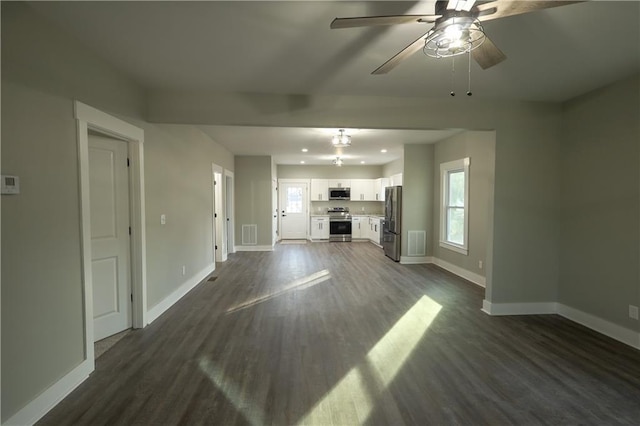 unfurnished living room featuring plenty of natural light, baseboards, and dark wood-type flooring