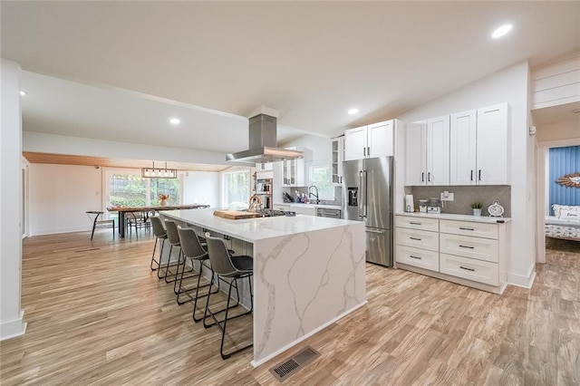 110 W Putnam Ferry Rd, Woodstock, GA 30189 - kitchen with stainless steel fridge with ice dispenser, island range hood, a kitchen breakfast bar, white cabinets, and light wood finished floors