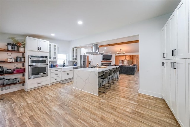 110 W Putnam Ferry Rd, Woodstock, GA 30189 - kitchen with appliances with stainless steel finishes, extractor fan, a breakfast bar area, open floor plan, and light wood-type flooring