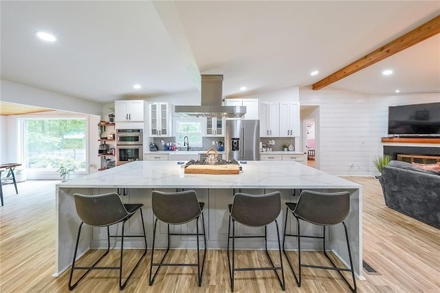 110 W Putnam Ferry Rd, Woodstock, GA 30189 - kitchen with appliances with stainless steel finishes, white cabinetry, a glass covered fireplace, light wood-style floors, and beamed ceiling