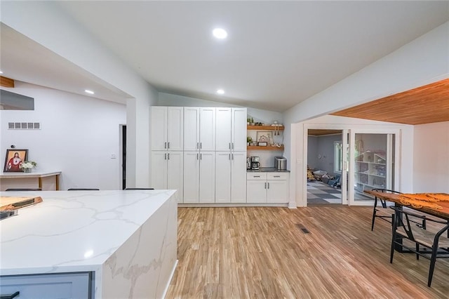 110 W Putnam Ferry Rd, Woodstock, GA 30189 - kitchen featuring lofted ceiling, open shelves, light wood-style floors, white cabinetry, and light stone countertops