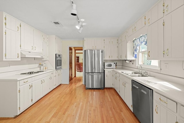 kitchen with white cabinets, track lighting, light wood-type flooring, sink, and stainless steel appliances