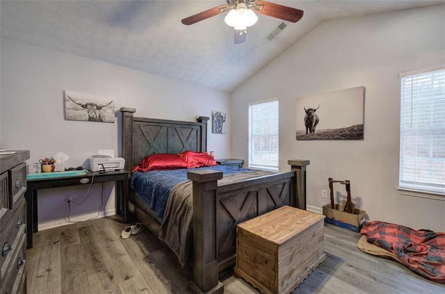 bedroom featuring ceiling fan, hardwood / wood-style floors, a textured ceiling, and vaulted ceiling