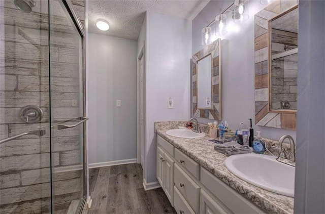 bathroom with vanity, a shower with door, hardwood / wood-style floors, and a textured ceiling