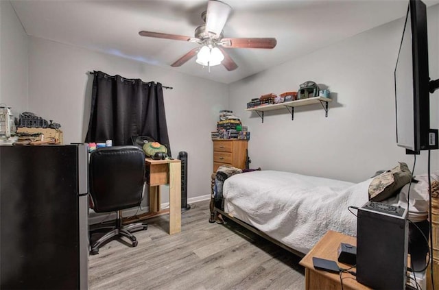 bedroom with ceiling fan, light hardwood / wood-style floors, and stainless steel fridge