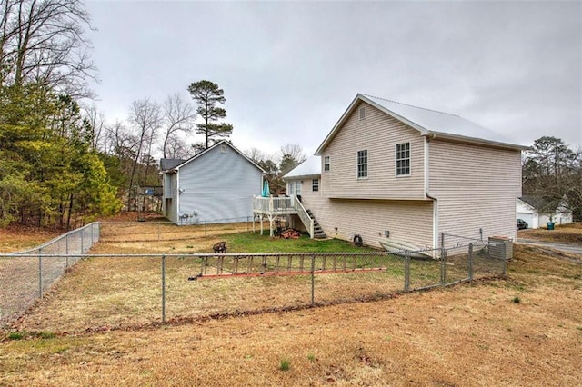 rear view of property with a wooden deck, central air condition unit, and a yard