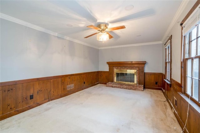 unfurnished living room with ceiling fan, ornamental molding, a fireplace, and light carpet