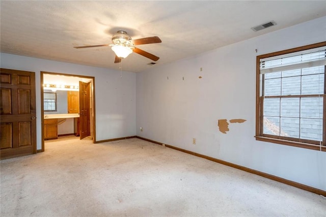 unfurnished bedroom with ensuite bath, light colored carpet, and ceiling fan