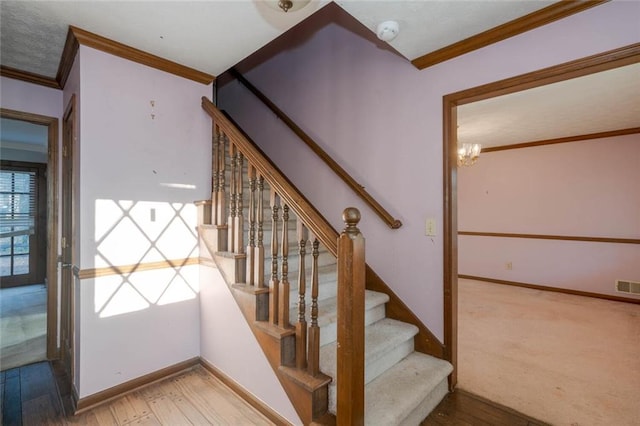 staircase featuring an inviting chandelier, hardwood / wood-style flooring, and ornamental molding