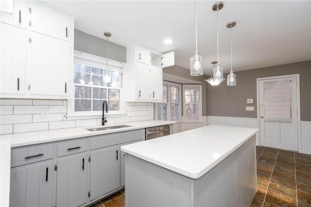 kitchen featuring a kitchen island, pendant lighting, tasteful backsplash, sink, and stainless steel dishwasher