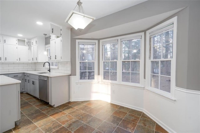 kitchen featuring tasteful backsplash, white cabinetry, dishwasher, sink, and hanging light fixtures