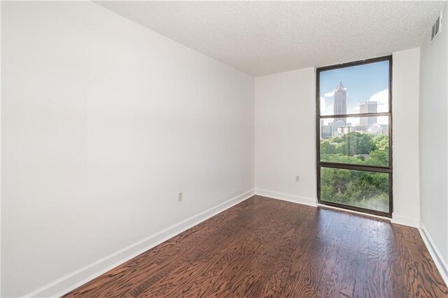 375 Ralph Mcgill Blvd NE Unit 807, Atlanta, GA 30312 - unfurnished room with a wall of windows, visible vents, baseboards, dark wood finished floors, and a textured ceiling