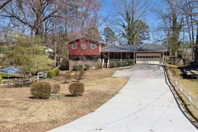 split level home featuring a porch, fence, a garage, and driveway