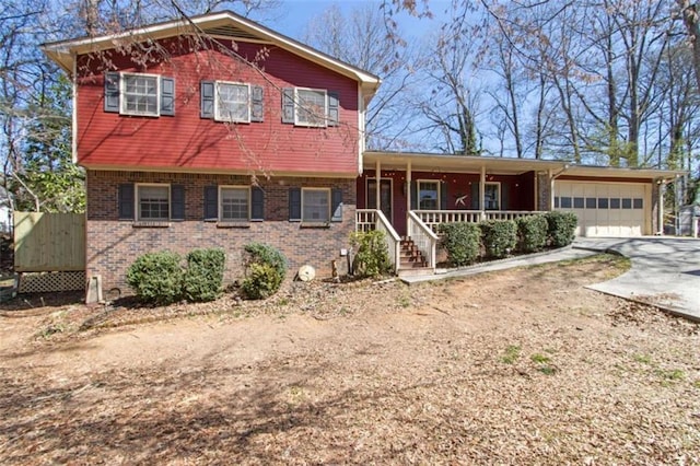 view of front of house featuring a porch, an attached garage, brick siding, and driveway