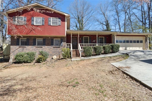 tri-level home with a porch, concrete driveway, brick siding, and an attached garage