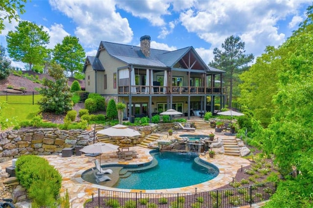 rear view of house with a swimming pool with hot tub and a patio area