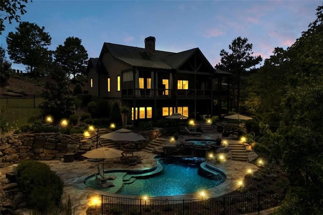 pool at dusk with an in ground hot tub and a patio