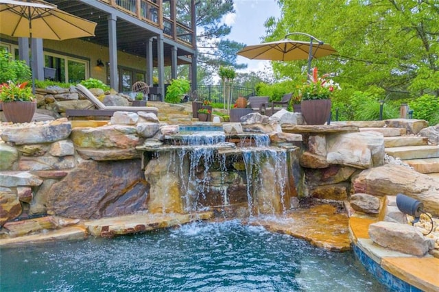 view of swimming pool featuring a small pond