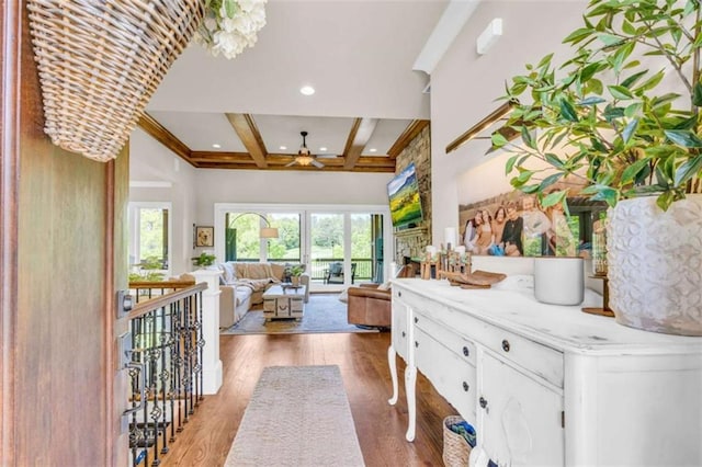 interior space with beam ceiling, ceiling fan with notable chandelier, coffered ceiling, and wood-type flooring