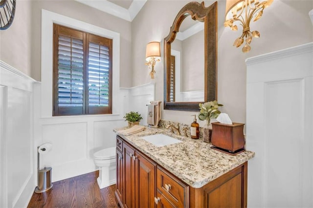 bathroom with wood-type flooring, vanity, toilet, and crown molding