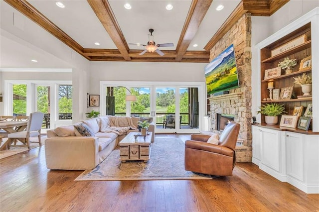 living room with light hardwood / wood-style flooring, ceiling fan, a fireplace, beamed ceiling, and a healthy amount of sunlight