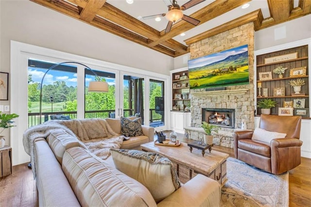 living room featuring beam ceiling, built in shelves, coffered ceiling, and wood-type flooring