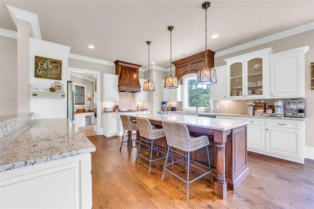 kitchen featuring white cabinets, pendant lighting, light hardwood / wood-style flooring, and tasteful backsplash