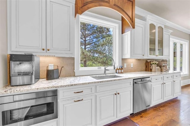 kitchen featuring white cabinets, decorative backsplash, stainless steel dishwasher, and sink