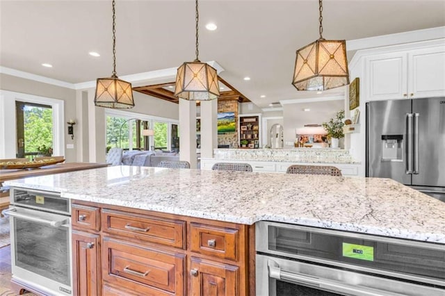 kitchen featuring a kitchen bar, hanging light fixtures, stainless steel appliances, and ornamental molding