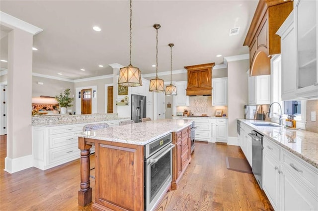 kitchen featuring tasteful backsplash, stainless steel appliances, white cabinets, a kitchen island, and hanging light fixtures