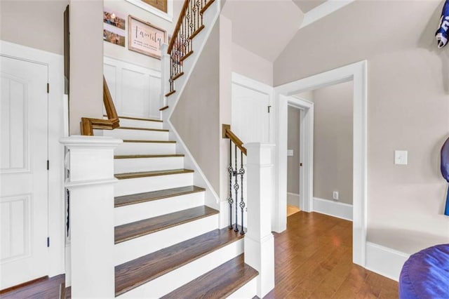 stairs featuring wood-type flooring and vaulted ceiling