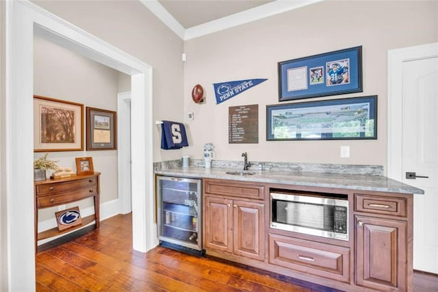 bar featuring sink, stainless steel microwave, beverage cooler, dark hardwood / wood-style floors, and ornamental molding