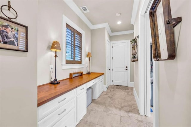 interior space with built in desk and crown molding