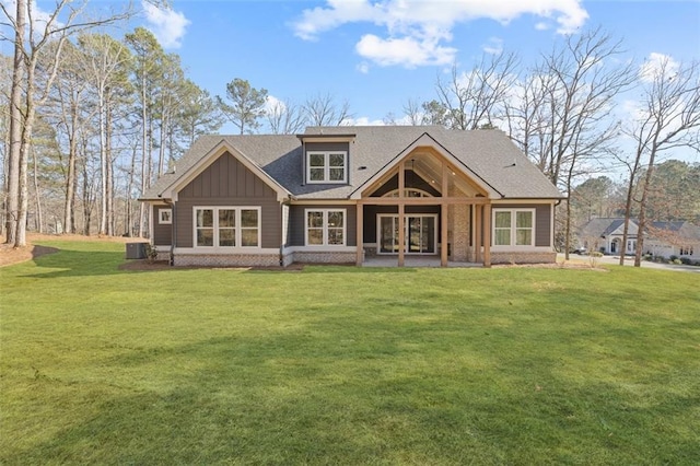 rear view of house featuring central AC unit, a lawn, board and batten siding, and roof with shingles