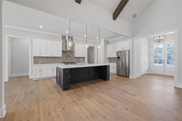 kitchen featuring light countertops, decorative backsplash, appliances with stainless steel finishes, white cabinets, and wall chimney range hood