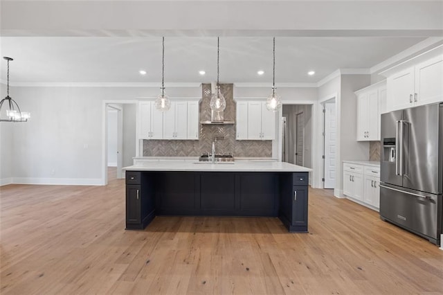 kitchen featuring tasteful backsplash, light countertops, wall chimney range hood, and high end refrigerator