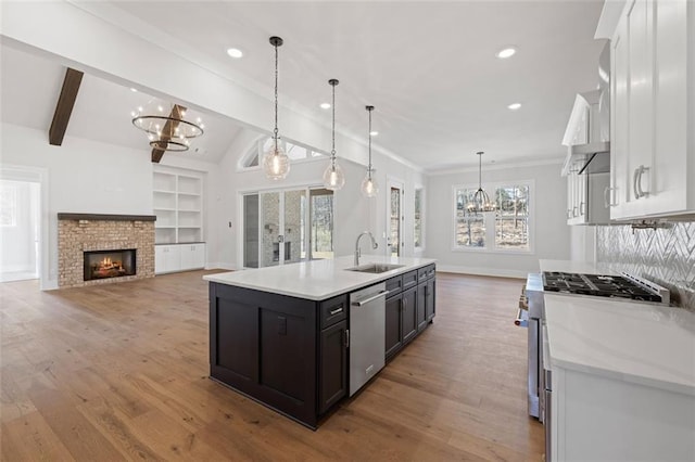 kitchen featuring white cabinets, an inviting chandelier, stainless steel appliances, light countertops, and a sink