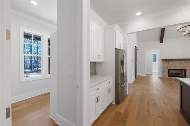 kitchen with open floor plan, light wood finished floors, stainless steel fridge, and white cabinetry