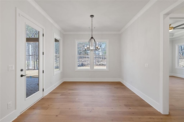 unfurnished dining area with baseboards, light wood-type flooring, an inviting chandelier, and crown molding