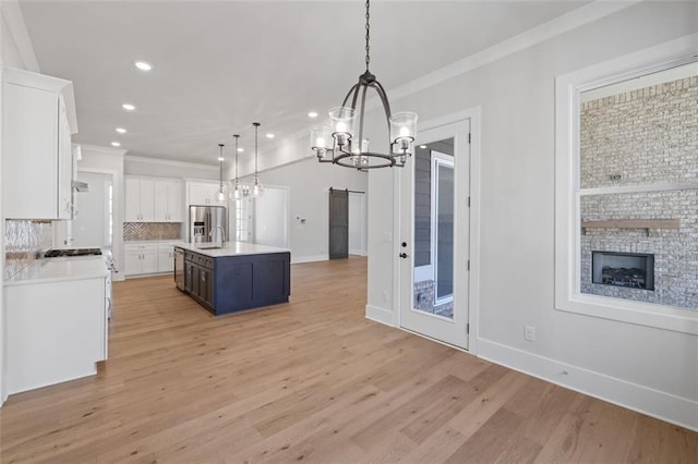 kitchen with a barn door, appliances with stainless steel finishes, white cabinets, and backsplash