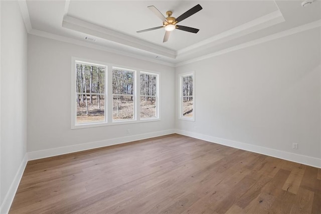 empty room featuring a ceiling fan, a tray ceiling, baseboards, and wood finished floors