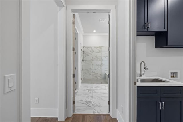 bathroom with baseboards, ornamental molding, marble finish floor, a tile shower, and vanity