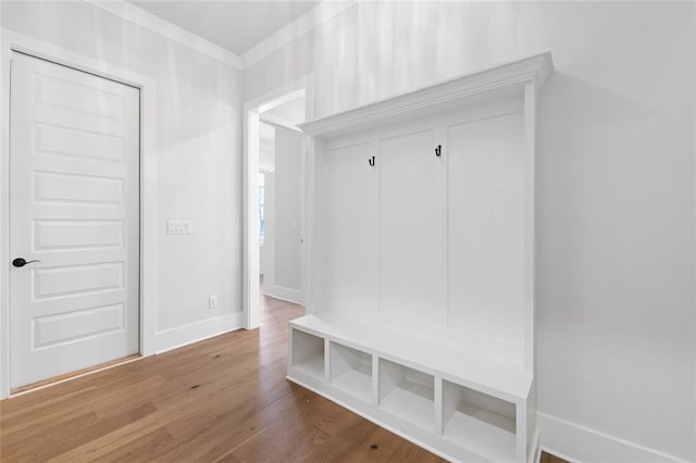 mudroom with crown molding, baseboards, and wood finished floors